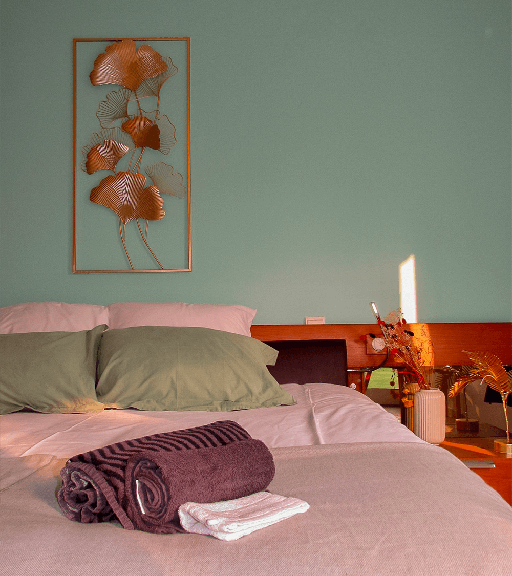 Chambre avec lit double, draps et décoration florale au mur