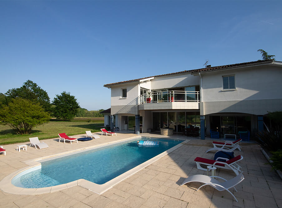 Terrasse avec domaine du haou en fond, piscine, transat et parc