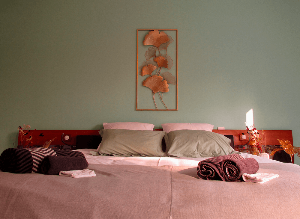 Chambre avec lit double, draps et décoration florale au mur