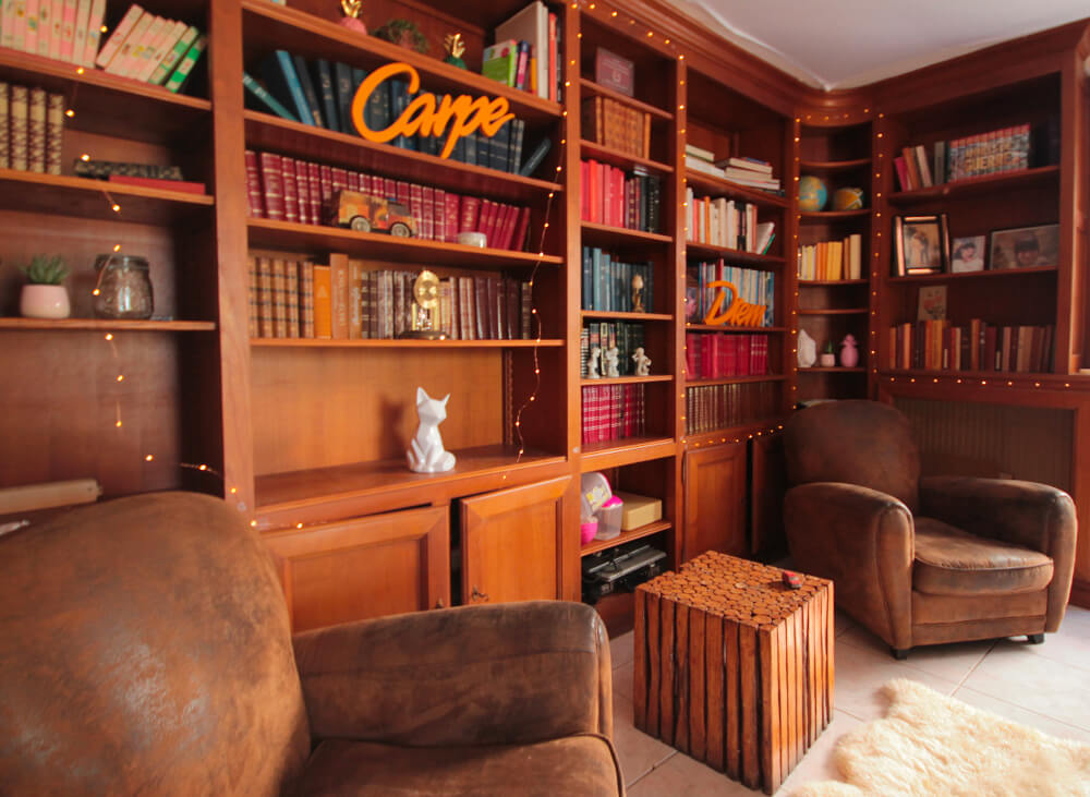 Salon de détente avec des fauteuils marrons et des étagères en bois